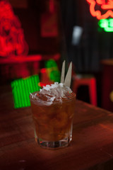 Glass with a cocktail on a table of a bar with colored lights