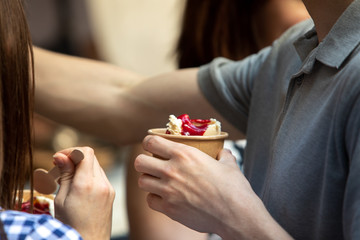 friends eating ice cream outdoors. hands holding cups close-up