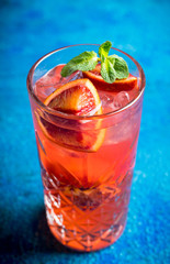 Red cocktail with blood oranges and mint on the rustic background. Selective focus. Shallow depth of field.
