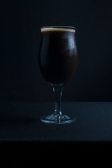 This bowl is made of crystal. The beer is a Dry Stout with grape must Tannat, Cabernet Franc, and Petit Verdot. Photo produced in low light, black background, lower exposure.