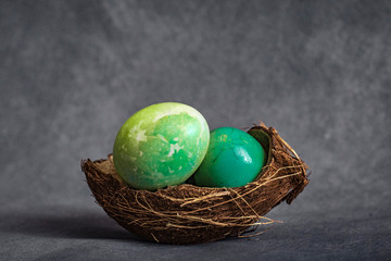 Easter eggs in a coconut shell on a gray background with coffee beans around