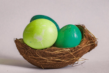 Easter eggs in a coconut shell on a gray background with coffee beans around