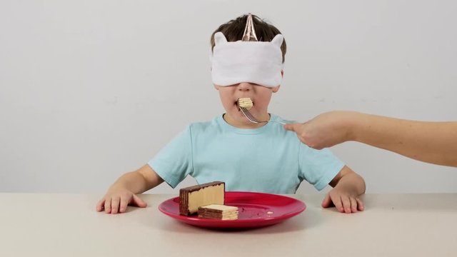 Little boy in a mask tries and guesses waffles with chocolate