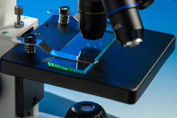 Close up photo of a microscope lenses examining glass sample