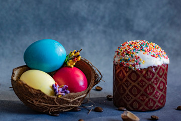 Easter eggs in a coconut shell on a gray background with coffee beans around