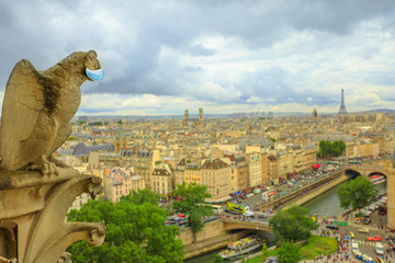 Statue of gargoyle with surgical mask, symbol of Paris city during Covid-19 pandemic. French...