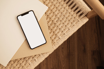Blank touch screen mobile phone on wicker background. Flat lay, top view empty copy space mockup...