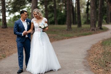 Fototapeta premium Smiling bride and groom walking in the park