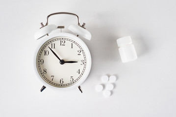 Insomnia problem concept. Alarm clock and pills on a blue background