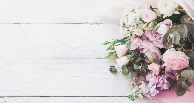 a large and beautiful bouquet of fresh roses, eustoma, matiola, freesia, eucalyptus, hydrangea in delicate pink and white colors, on a white wooden background in the style of Provence. Copy space.