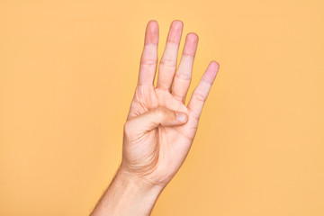 Hand of caucasian young man showing fingers over isolated yellow background counting number 4 showing four fingers
