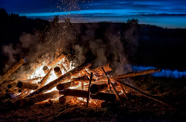 Burning logs in orange red bonfire at night