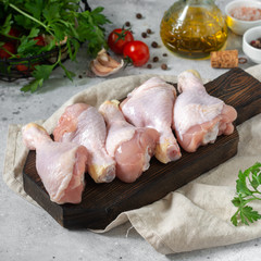 A chicken drumstick on a wooden Board on the light gray kitchen table. Raw chicken drumstick in the process of cooking. Chicken leg