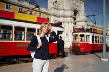 Traveling by Portugal. Happy young woman with rucksack walking by street in Lisbon.