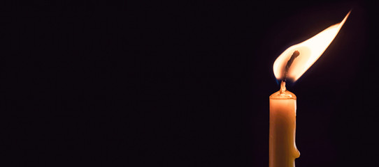 a burning candle on a dark background. Close up.