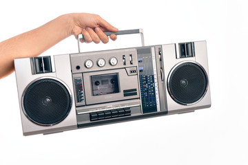 Hand of caucasian young man holding vintage radio cassette over isolated white background