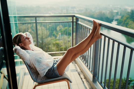 Young Woman Enjoying Park View From Balcony.