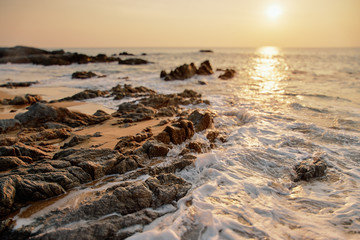 Fototapeta na wymiar Beautiful sunset seascape with rock on sand beach.