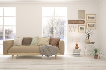 Fototapeta premium White living room with sofa and winter landscape in window. Scandinavian interior design. 3D illustration