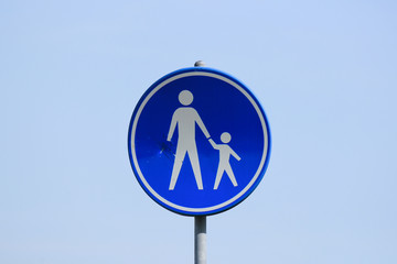 Damaged Dutch pedestrian road sign with blue sky