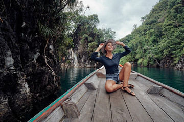 Fototapeta na wymiar Happy vacation in Thailand. Pretty young woman taking sailing Khao Sok National Park lake on traditional longtail boat.