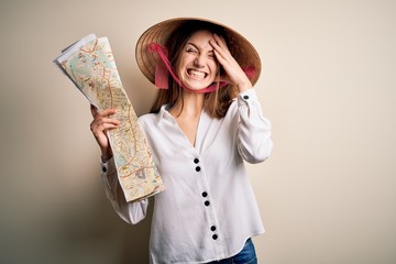 Young beautiful redhead woman wearing asian traditional hat holding city map stressed with hand on head, shocked with shame and surprise face, angry and frustrated. Fear and upset for mistake.