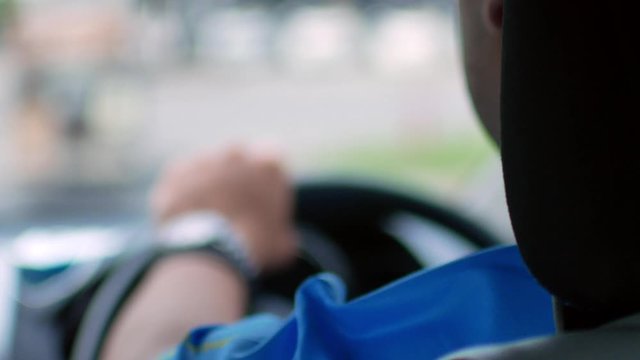 POV with selective focusing to hand holding car's steering wheel while driving a car.