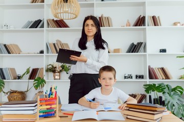 Portrait of smart tutor with pencil correcting mistakes in pupil?s notebook