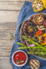 Hot vegetable salad. Set different grilled vegetables on a plate. Vegan barbeque picnic set, with asparagus, tomatoes, mushrooms, peppers, corn and sauces