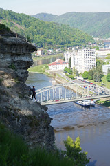 Fototapeta premium Woman climbing difficult steep wall above river and town, via ferrata route, Shepherd's Wall, Decin, Czech Republic