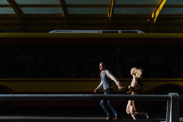 A young woman and a man are running near the bus.
