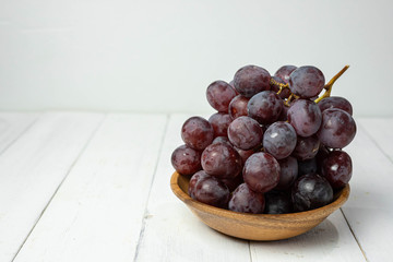 Blue grapes on white wooden background.
