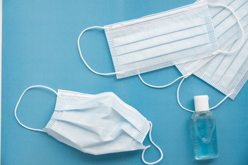 top view, on a blue background are new medical masks, hand antiseptic and one mask used. Background on the topic of protection during an outbreak
