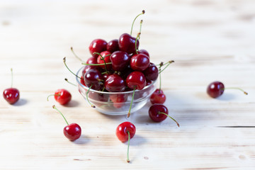ripe red cherries in a glass bowl on wooden table