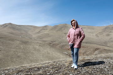 Woman posing on rocky ridge of Caucasus background