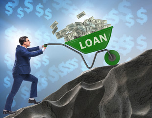 Businessman pushing wheelbarrow uphill in debt loan concept