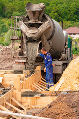 Fototapeta premium Construction worker laying cement or concrete into the foundation formwork