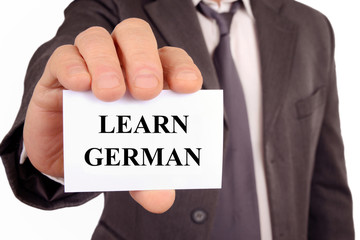 Man holding a card on which is written learn german