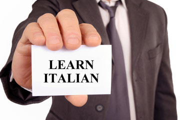 Man holding a card on which is written Learn Italian | Homme tenant une carte sur laquelle est écrit apprenez l'italien