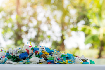 Fototapeta premium Bottle flake,PET bottle flake,Plastic bottle crushed,Small pieces of cut colorful plastic bottles with green bokeh background