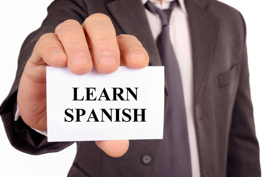 Man holding a card on which is written Learn Spanish