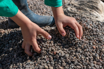 Child holding small colorful stones in little hands. Concept of game money, valuable resource