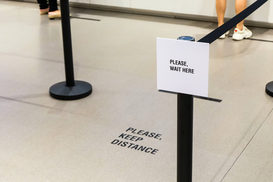 Please wait here and keep distance  sign in front of purchase counter in department store for people to wait in line. New normal for prevent and stay safe from Corona virus or Covid-19.