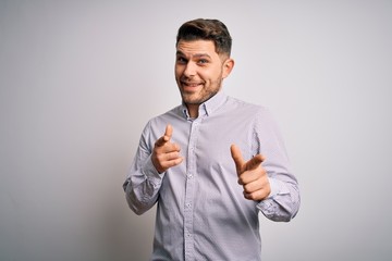 Young business man with blue eyes standing over isolated background pointing fingers to camera with happy and funny face. Good energy and vibes.