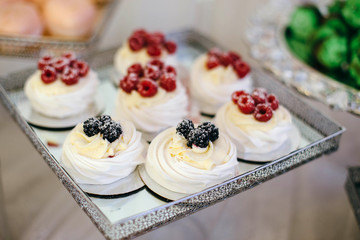 Pavlova cakes meringue dessert decorated with berries, close up. Soft focus. Delicious for welcome snacks for each guest.