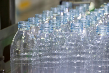 The PET bottles  on the conveyor belt for filling process in the drinking water factory. The hi-technology of plastic bottle manufacturing process.