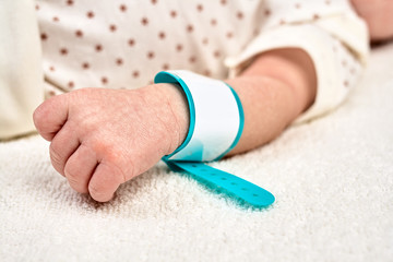Hand of a newborn baby with a identification bracelet tag name