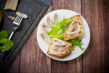 sandwich with salad, herring and herbs with onions in a plate
