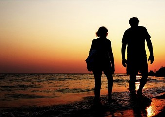Couple walking along the shore at sunset