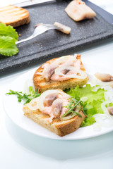 sandwich with salad, herring and herbs with onions in a plate
